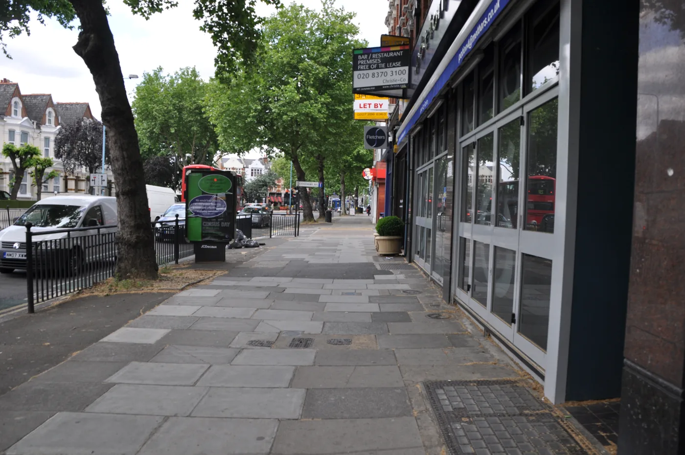 Chiswick High Road. Household waste bagged at the kerb outside the shops.